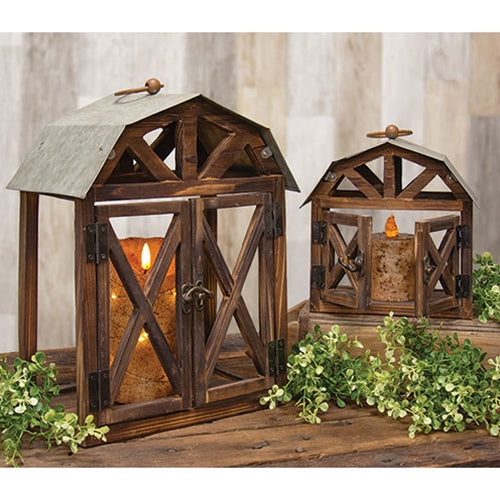Rustic wood and metal barn-shaped lanterns with open sides, detailed roofs, and swinging doors, perfect for decor.